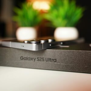 Close-up of Samsung Galaxy S25 Ultra box with smartphone and decorative plants in background.