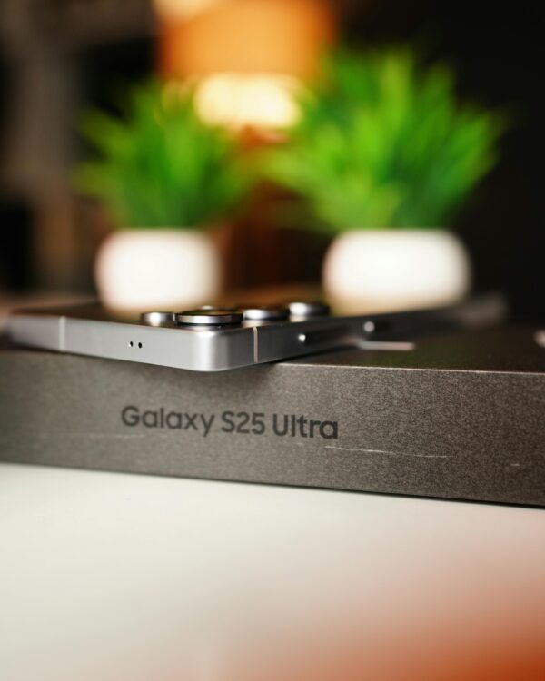 Close-up of Samsung Galaxy S25 Ultra box with smartphone and decorative plants in background.